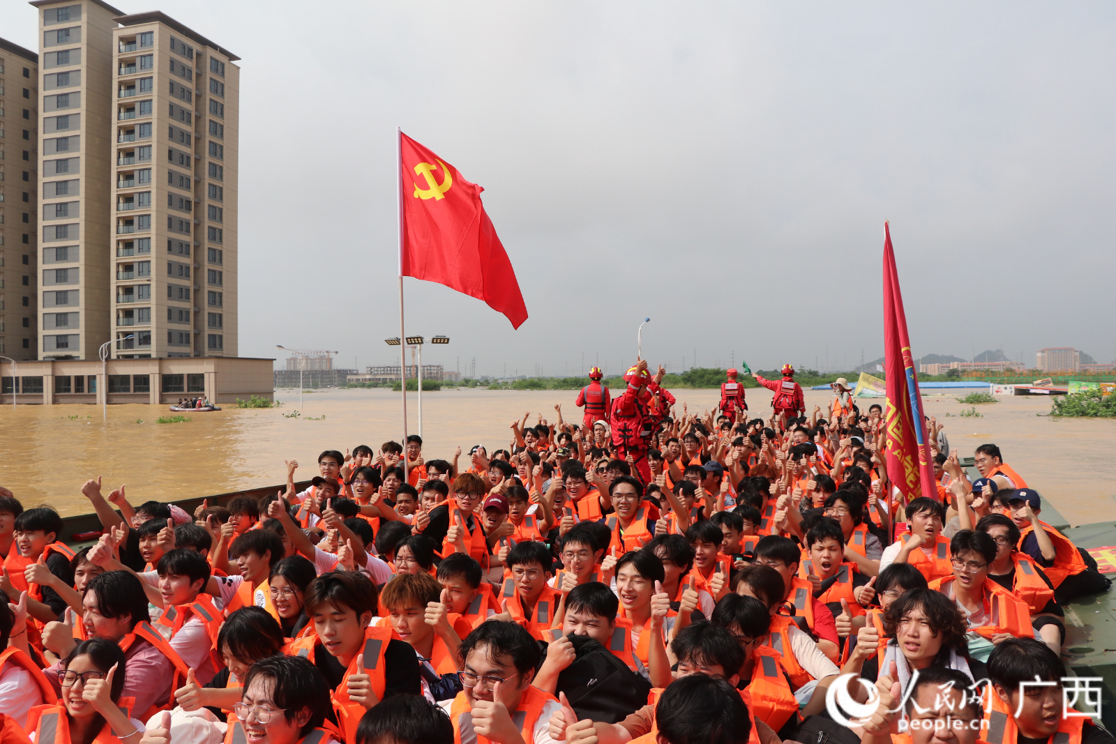 广西物流职业技术学院学生乘坐动力舟桥前往安全地带,他们竖起大拇指向救援人员致敬。
